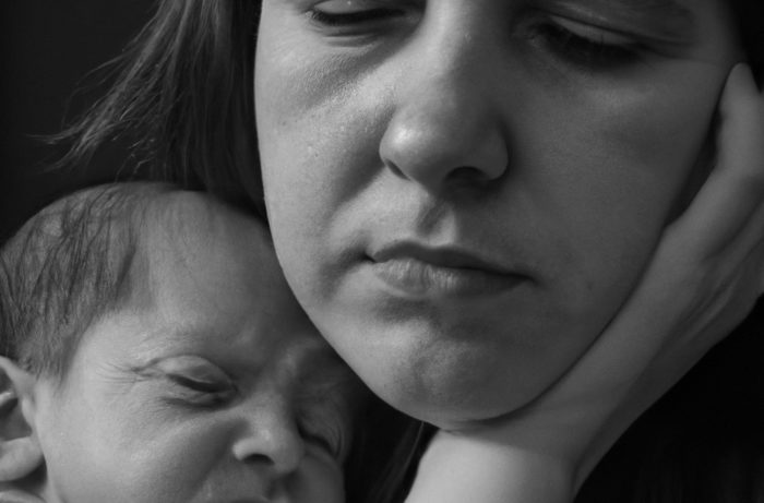 DALL·E 2022-10-09 22.41.37 &#8211; A realistic photograph of a mother suffering from a post-partum depression holding her baby